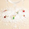 Six beaded Christmas wine glass charms attached to stems of glasses on fake snow.