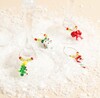 Six beaded Christmas wine glass charms attached to stems of glasses on fake snow close up.