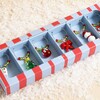Close-up of festive beaded wine charms displayed inside a striped gift box.