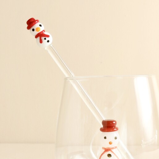 Close up of a clear glass drink stirrer with a snowman topper in a glass