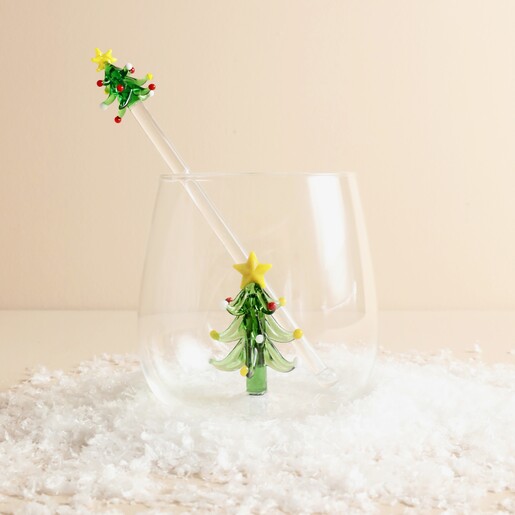 Clear glass drink stirrer topped with a green Christmas tree inside a tumbler
