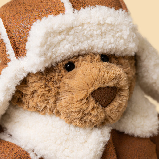 Close-up portrait of Jellycat Bartholomew Bear in a fleece-trimmed winter trapper hat