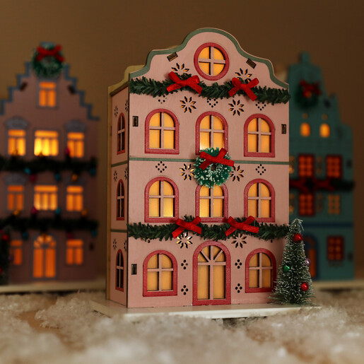 Illuminated wooden pink house Christmas decoration glowing with warm LED light