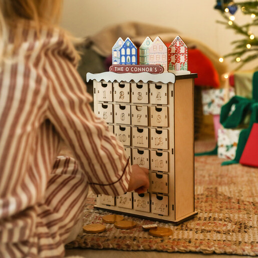 Child opening a drawer on a personalised wooden townhouse advent calendar