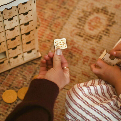 Hand holding an engraved wooden activity token from the advent calendar