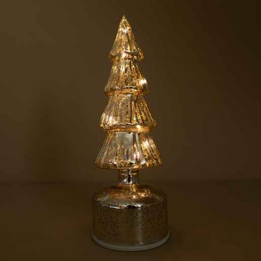 Illuminated silver glass Christmas tree rotating decoration glowing in warm light