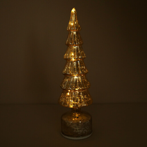 Gold ribbed glass Christmas tree illuminated with warm internal rotating LED lights in dark