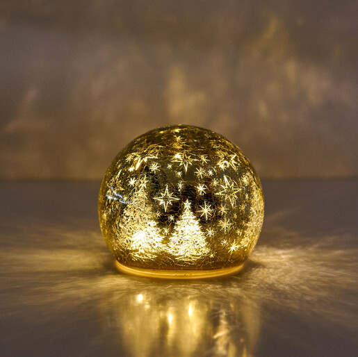 Illuminated small golden crackle glass snow globe with glowing fir tree and star silhouettes.