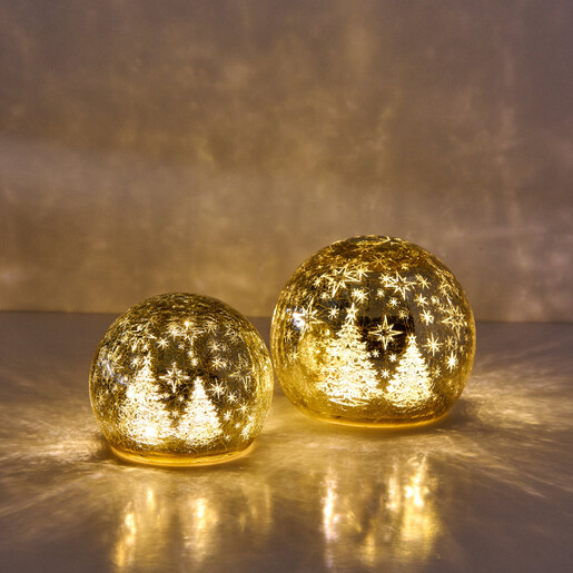 Small and large illuminated golden glass snow globe lights glowing side by side