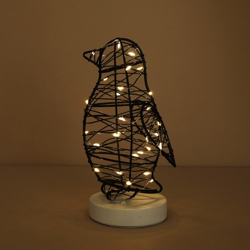 Illuminated wire penguin light with warm glowing fairy lights in the dark