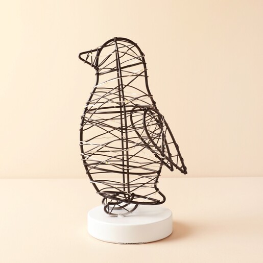 Freestanding black wire penguin light on a round white base
