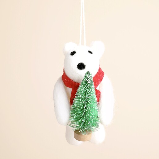 Close up of white felt polar bear decoration wearing red scarf and holding mini tree
