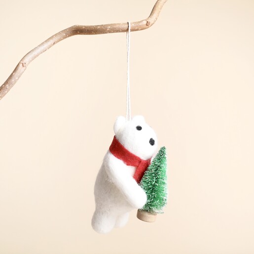 Side view of felt polar bear decoration with red scarf holding mini Christmas tree