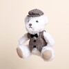 Close up of plush boy bear Christmas decoration wearing houndstooth waistcoat and cap