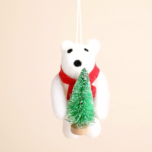 Close up of white felt polar bear decoration wearing red scarf and holding mini tree