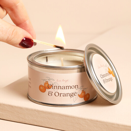 Hand lighting the wick of a Cinnamon and Orange paint pot candle