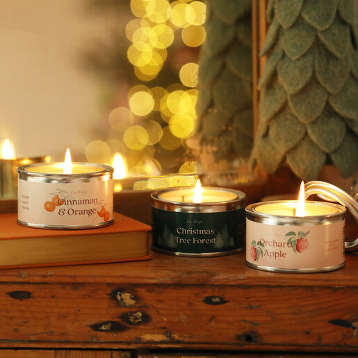 Three lit paint pot tin candles styled on a wooden shelf