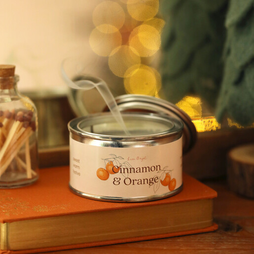 Extinguished Cinnamon and Orange candle with smoke rising against a festive background