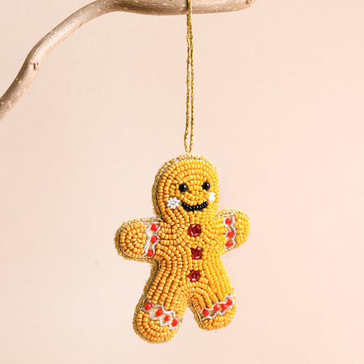 Beaded gingerbread man hanging decoration suspended from a wooden branch