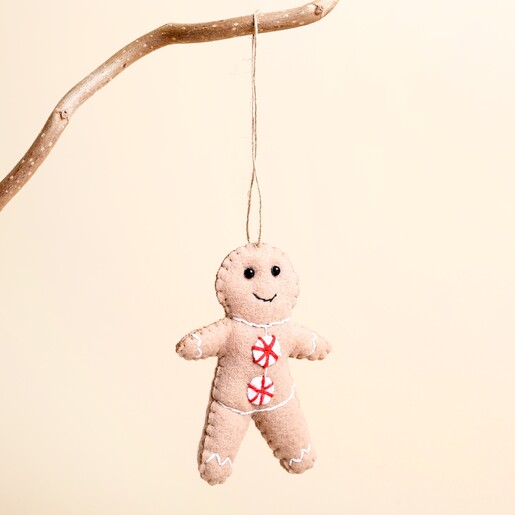 Felt gingerbread man hanging decoration suspended from a rustic twig branch