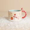 Small ceramic Christmas mug with snowman motif and candy cane handle on faux snow