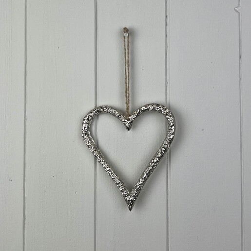 Full view of textured silver metal heart hanging decoration on white wooden wall