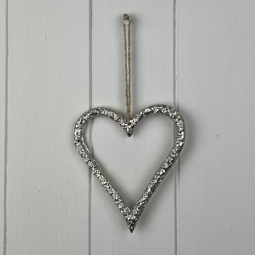 Textured silver open heart hanging decoration suspended by rustic twine against white panelling