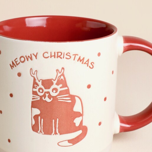 Close-up of festive cat with glasses and antlers on ceramic Christmas mug