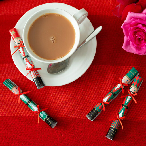 Nutcracker saucer crackers placed beside a cup of tea on a red background