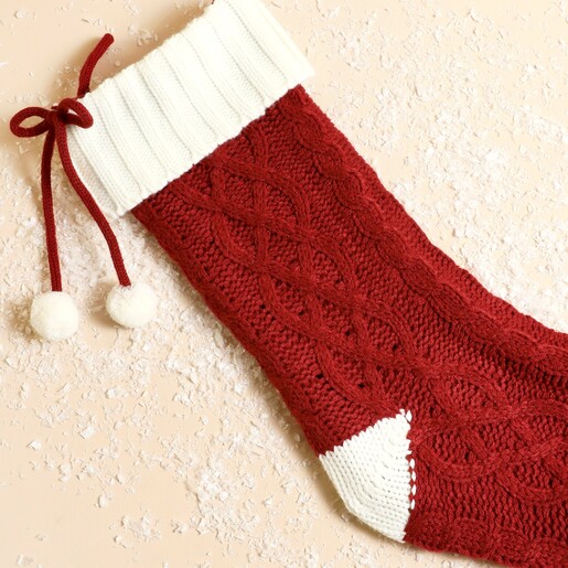 Close up of the white ribbed cuff and pom-pom ties on knitted stocking