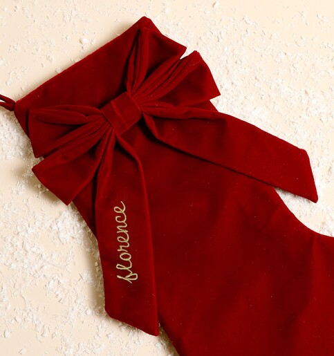Close up of the red velvet bow embroidered with a name in metallic gold script