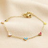 Rainbow Enamel Tiny Heart Charm Bracelet in Gold on Beige Fabric