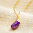 Close Up on Aubergine Pendant Necklace in Gold on Beige Fabric