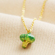 Close Up of Broccoli Pendant Necklace in Gold on Beige Fabric