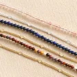 Brown Double Layer Stone Beaded Bracelet in Gold With Other Available Styles on Beige Fabric