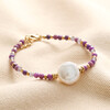 Purple Crystal and Pearl Beaded Bracelet on top of a beige fabric