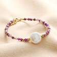 Purple Crystal and Pearl Beaded Bracelet on top of a beige fabric