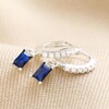 Blue Stone and Crystal Charm Huggie Hoop Earrings in Silver on Beige Fabric