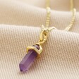 Amethyst Crystal Point Pendant Necklace in Gold on beige fabric