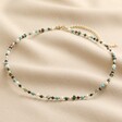 Semi-Precious Stone Bead Necklace in Blue and Green laid out on top of beige coloured fabric