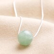 Green Semi-Precious Stone Ball Pendant Necklace in Silver on top of Beige Coloured Fabric